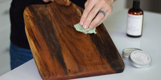Rubbing Arbor Novo Miracle Balm on wood serving board.