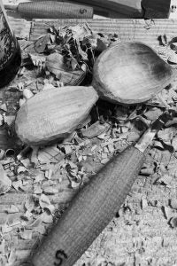 Svante Djärv wood carving spoon knife and a handmade wooden coffee scoop in a pile of wood chips.